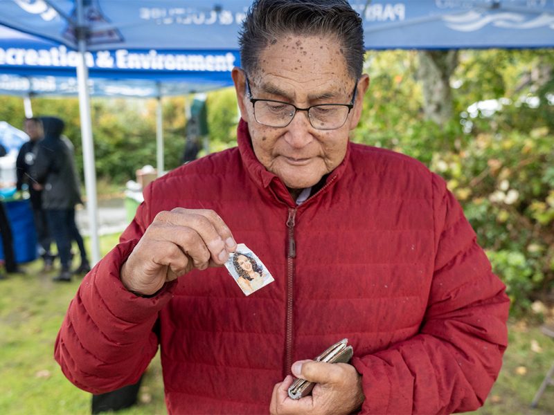 Lisa Marie Young's photo, taken when she was 16, is taken out of a wallet and shown by her grandfather who is wearing a red jacket.