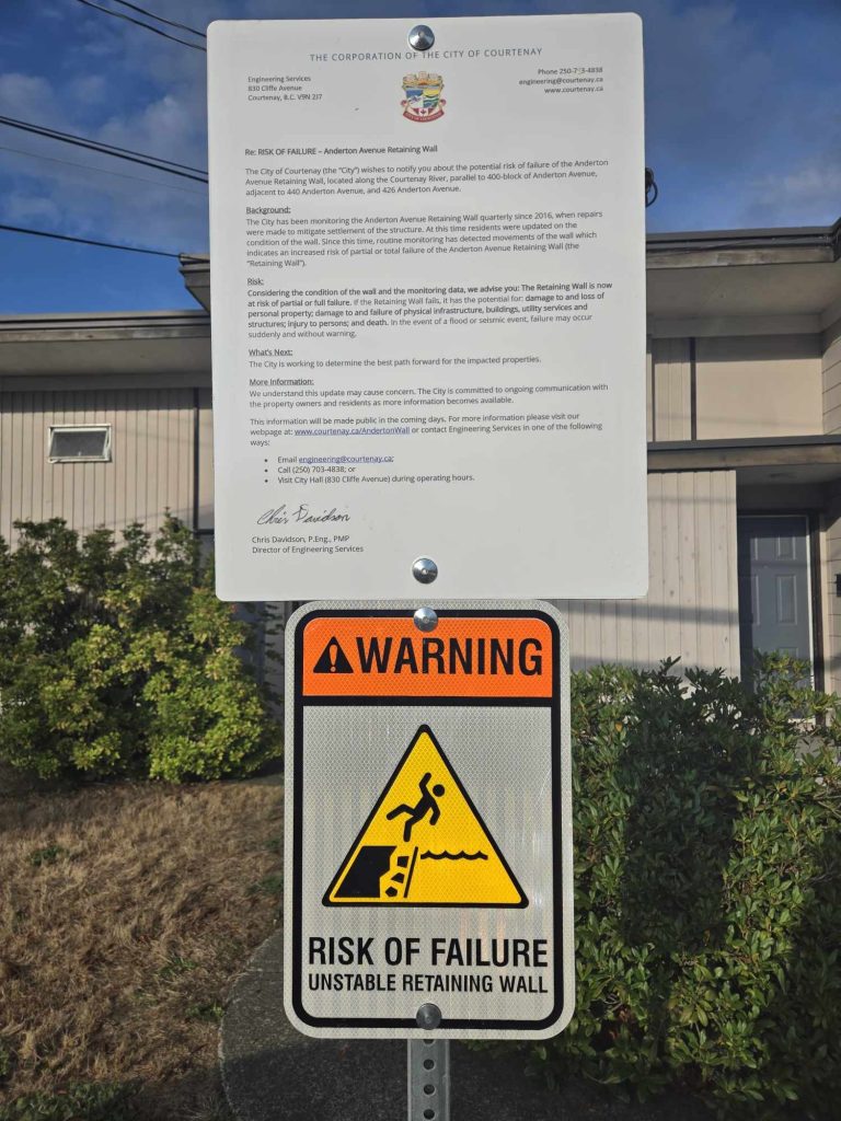Warning sign and a notice in front of the apartment complex. “If the retaining wall falls, it has the potential for: damage to and loss of personal property, damage to and failure of physical infrastructure, buildings, utility services and structures; injury to persons; and death,” the notice reads, above another warning sign that says "warning, risk of failure"