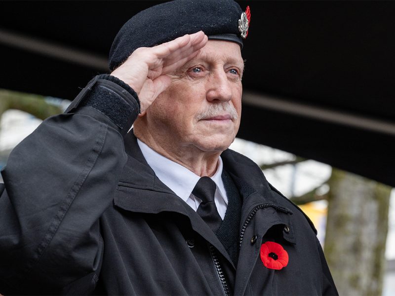 A veteran wearing a black beret and a black jacket with a red poppy salutes during the Remembrance Day ceremony in Nanaimo, British Columbia on Nov. 11, 2024