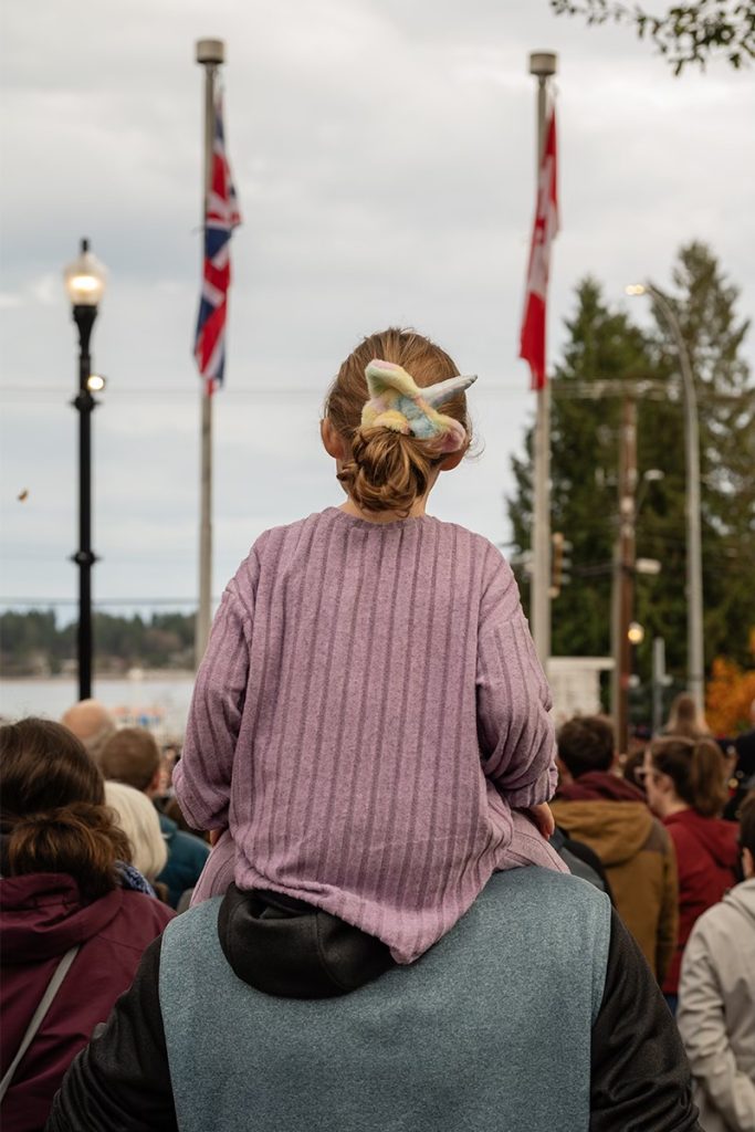 A young girl sits on her father’s shoulders as she watches the Remembrance Day ceremony in Nanaimo on Nov. 11, 2024.