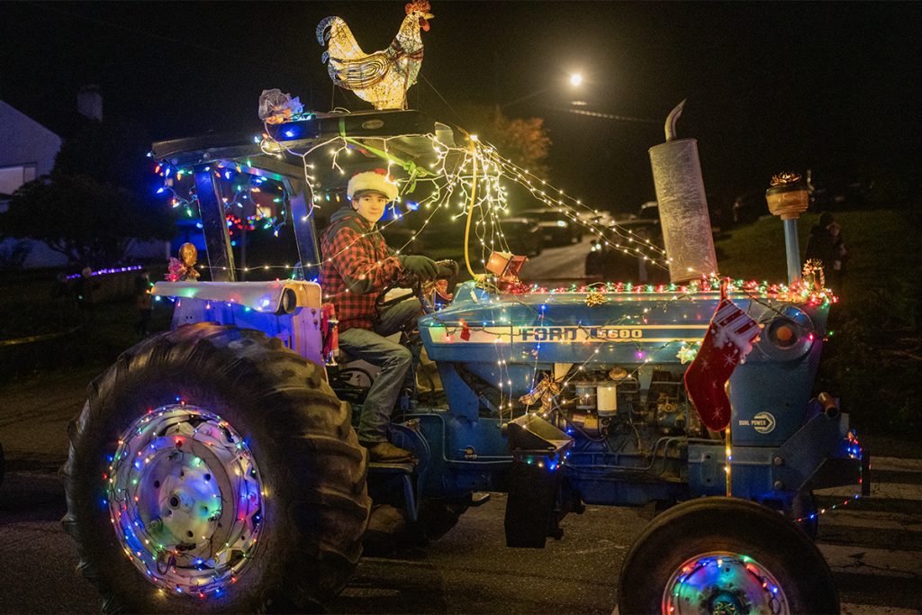 An antique Ford 5600 tractor with Christmas lights and a light up rooster on the top.
