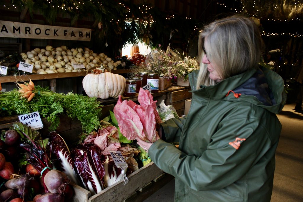 A woman holds up a bright pink vegetable.