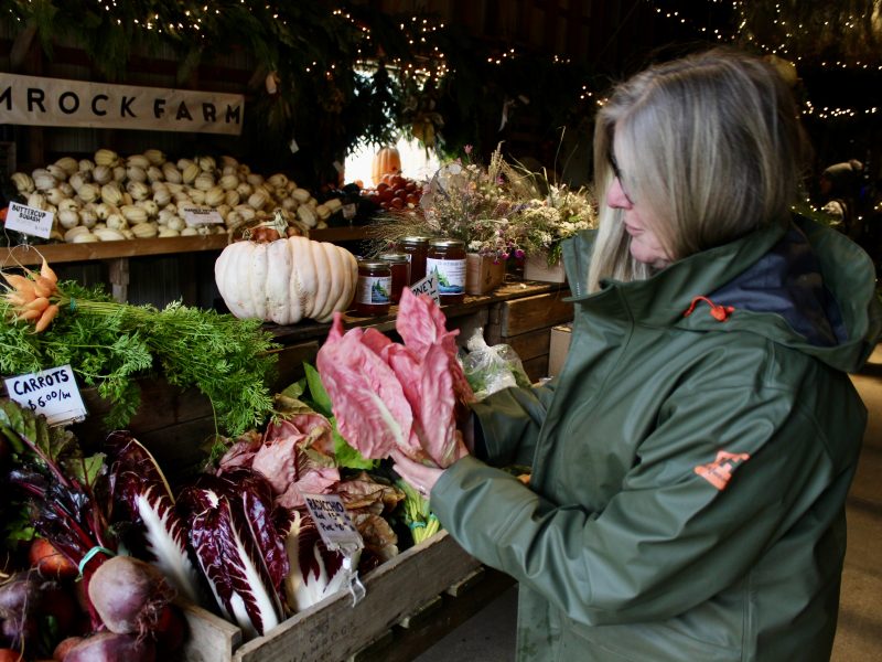A woman holds up a bright pink vegetable.