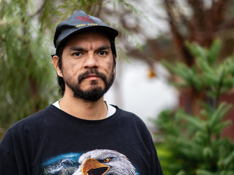 Photo of a man with a beard wearing a ball cap and a shirt with a bald eagle.