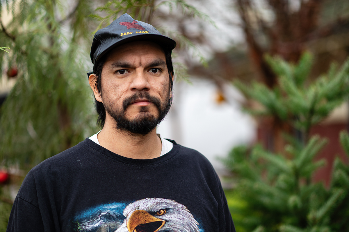Photo of a man with a beard wearing a ball cap and a shirt with a bald eagle.