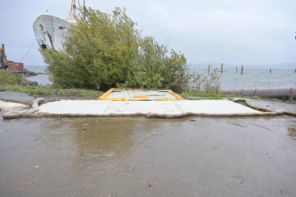 A large white drainaige area that looks similar to a cattle guard lies atop the beach at Deep Water Recovery’s site in Union Bay