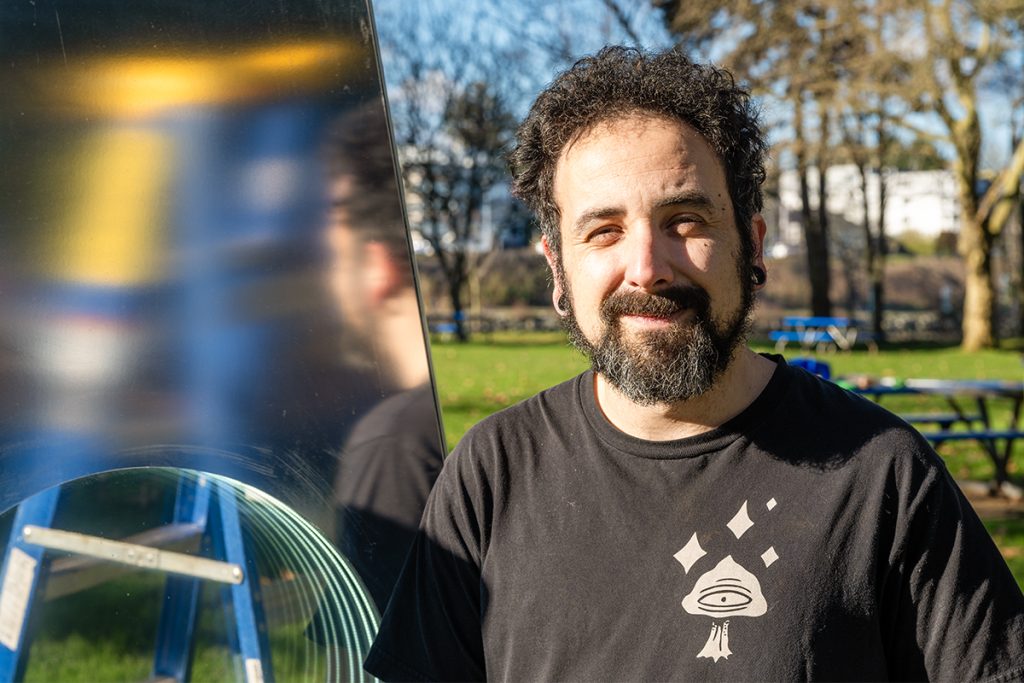 Luminous Paths artist Mauro Dalla Costa standing in front of an art installation in a park.