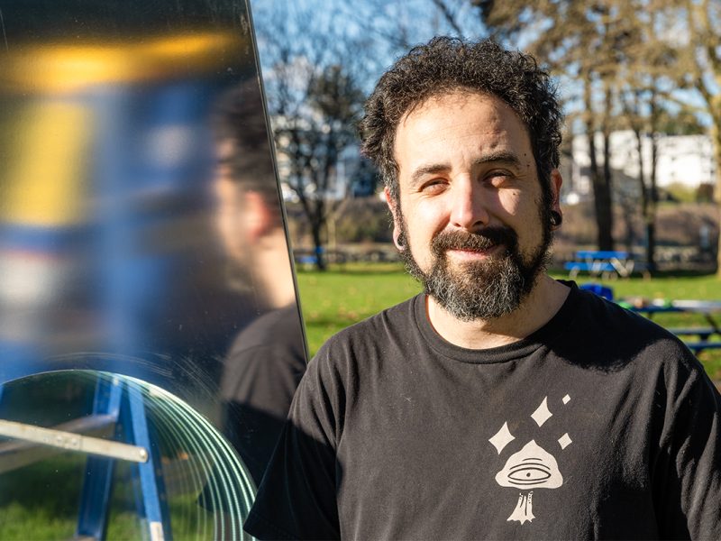 Luminous Paths artist Mauro Dalla Costa standing in front of an art installation in a park.