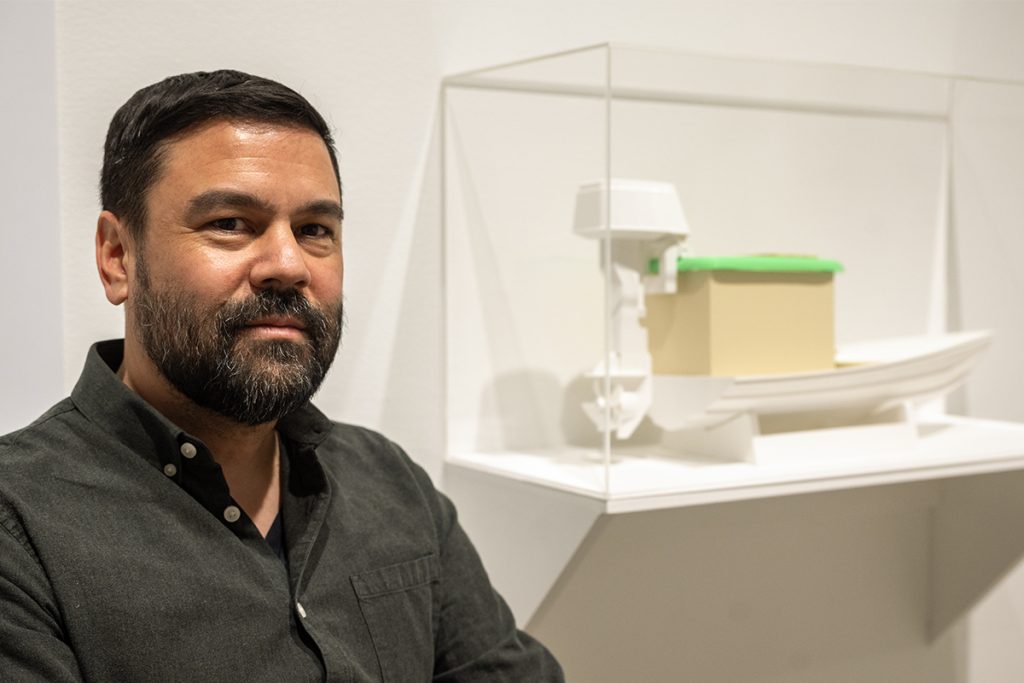 Jon Sasaki sits beside his design of a raceboat inspired by a Japanese ofuro bathtub,