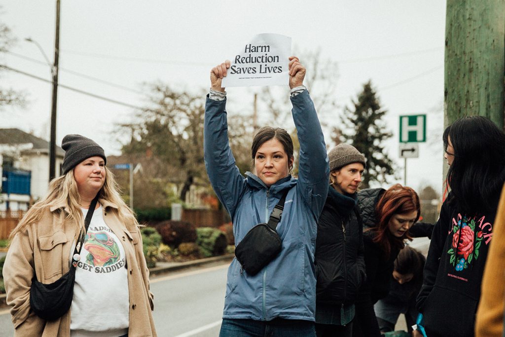 Dr. Kelsey Roden holds a sign that reads "Harm Reduction Saves Lives" while being forced off hospital property for trying to open an overdose prevention site at the Royal Jubilee Hospital in Victoria B.C. on November 18, 2024.