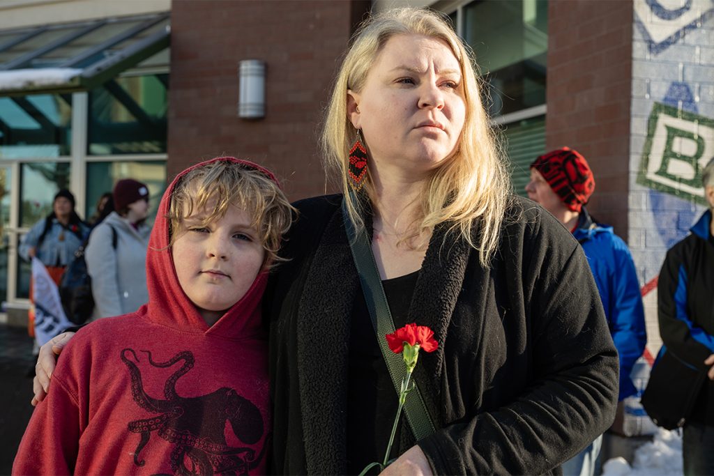 A woman holds a flower and has one arm around her son at a march for missing and murdered Indigenous women, girls and two-spirit people in Nanaimo on Feb. 14, 2025.