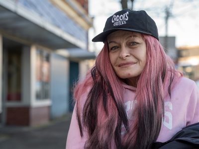 Photo of a woman with pink hair and a pink sweatshirt and black ball cap.