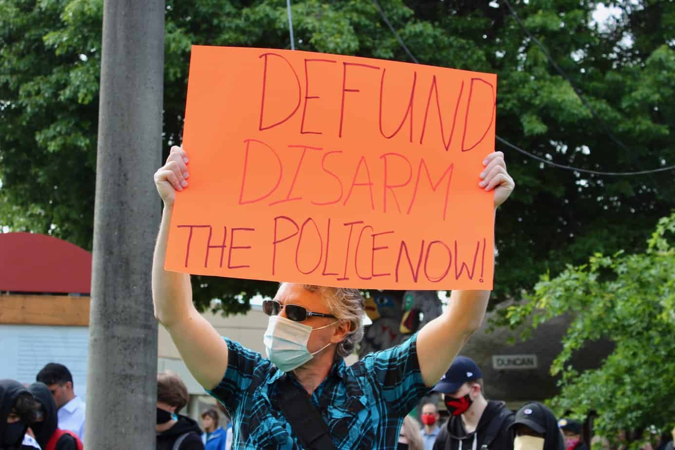 Man holding sign at a rally in Duncan.