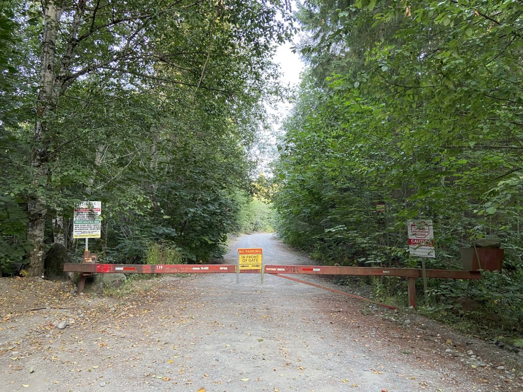 A gate blocks a road that heads into the forest on Vancouver Island.