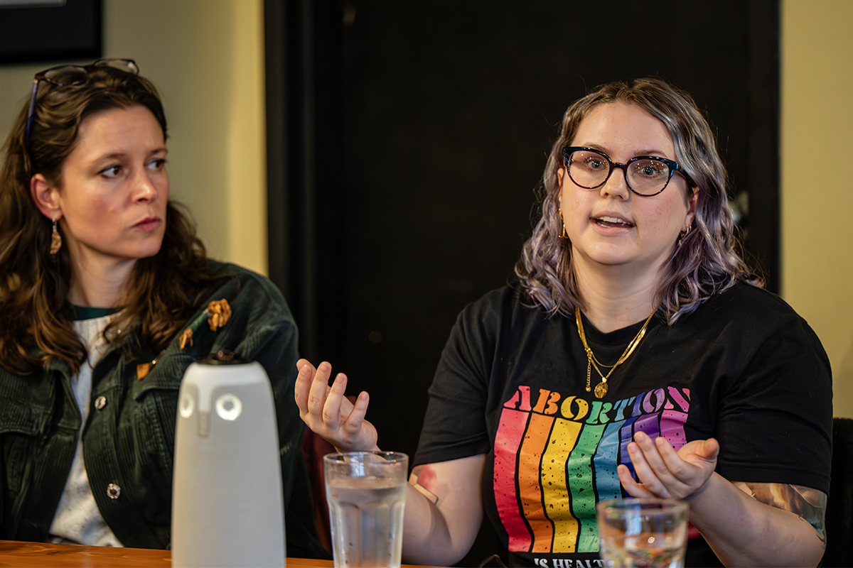 Laura Interlandi sits next to Dr. Emily Stuart and watches Stuart as she speaks