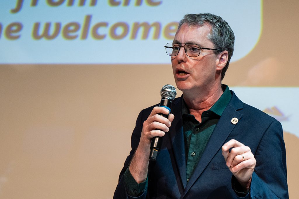 Photo of a man speaking into a microphone.