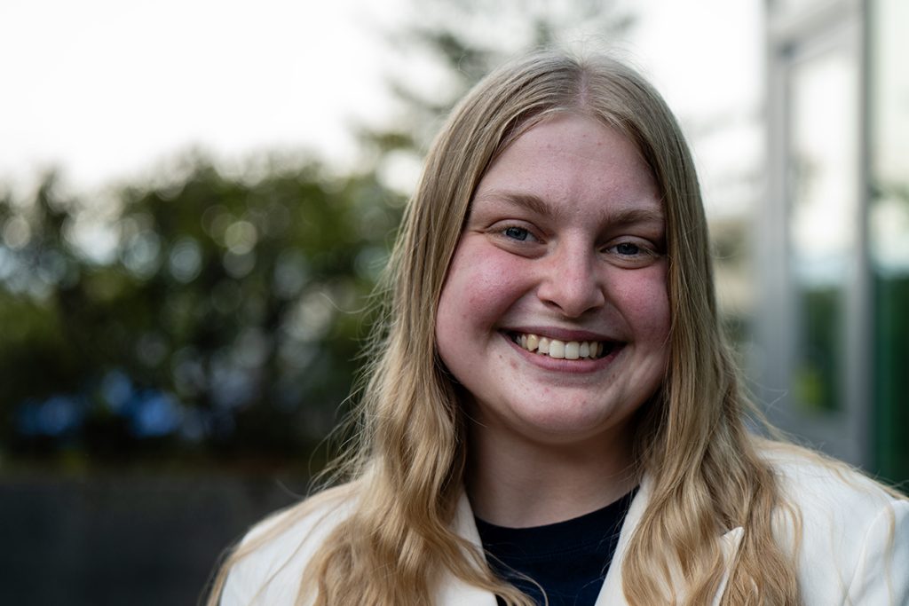Photo of a woman with blonde hair and wearing a white jacket