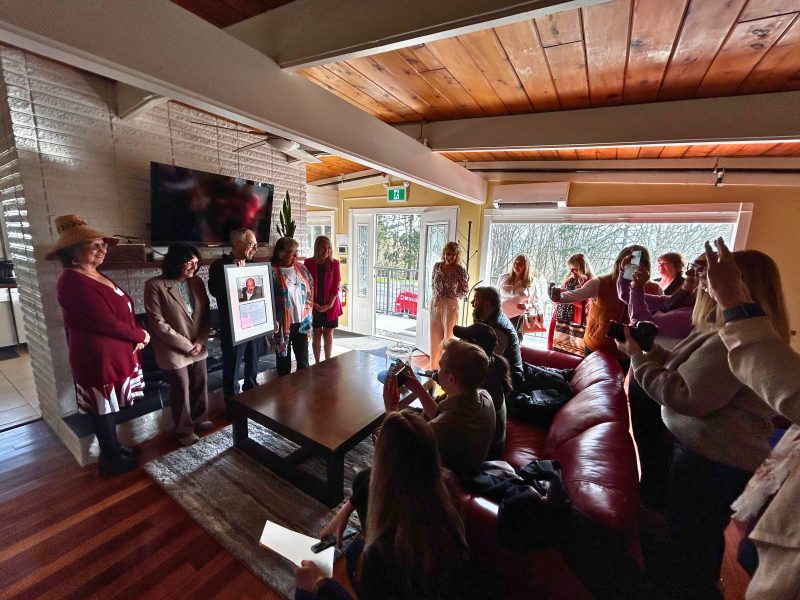 A group of people standing in a living room posing for a photo at the opening of a youth shelter.