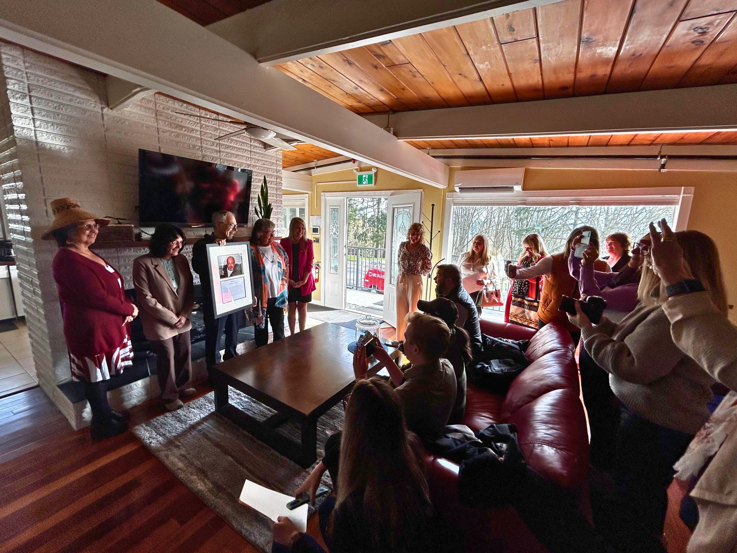 A group of people standing in a living room posing for a photo at the opening of a youth shelter.