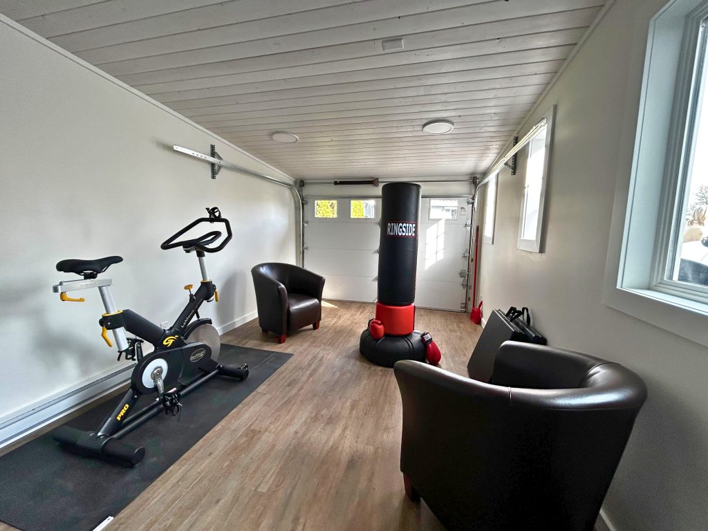 A room with a chair, an exercise bike and a punching bag.