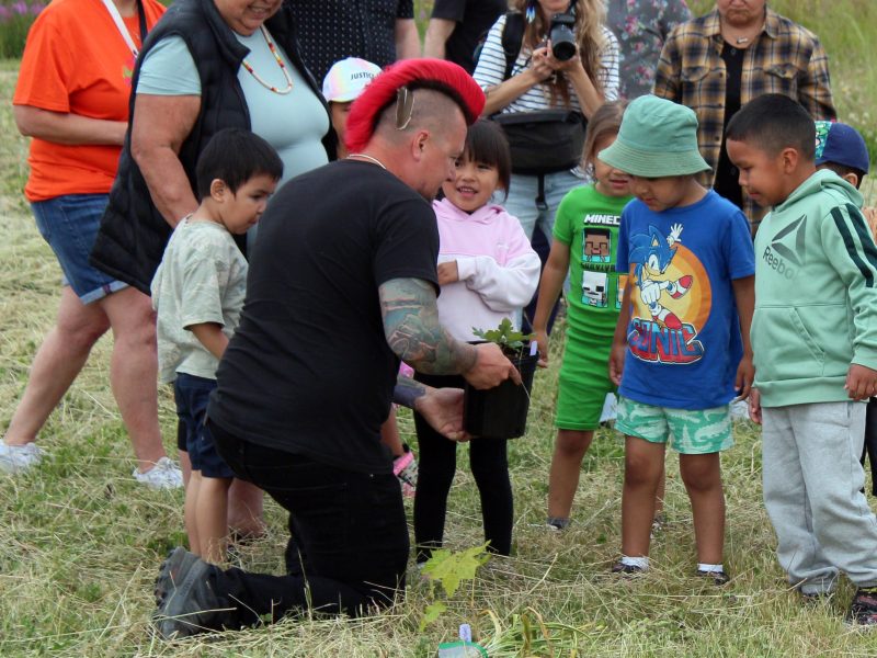 Jared Qwustenuxun Williams shows children from the Le'lum'uy'lh Daycare Centre examples of native plants from the nursery.