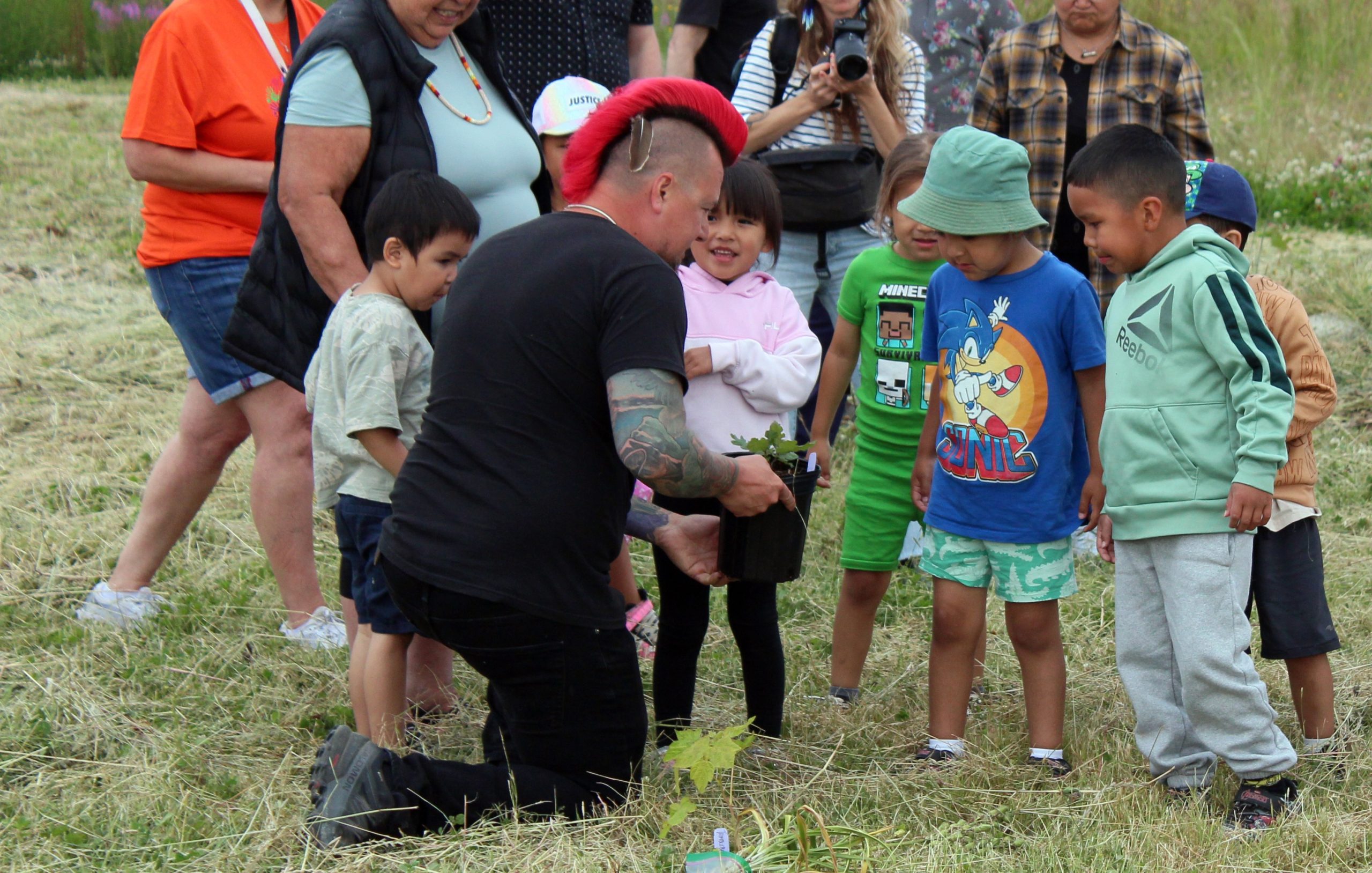 Jared Qwustenuxun Williams shows children from the Le'lum'uy'lh Daycare Centre examples of native plants from the nursery.