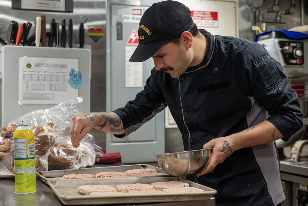 Cpl. Cameron Best, an army cook serving on HMCS Nanaimo, prepares hamburgers for the crew.