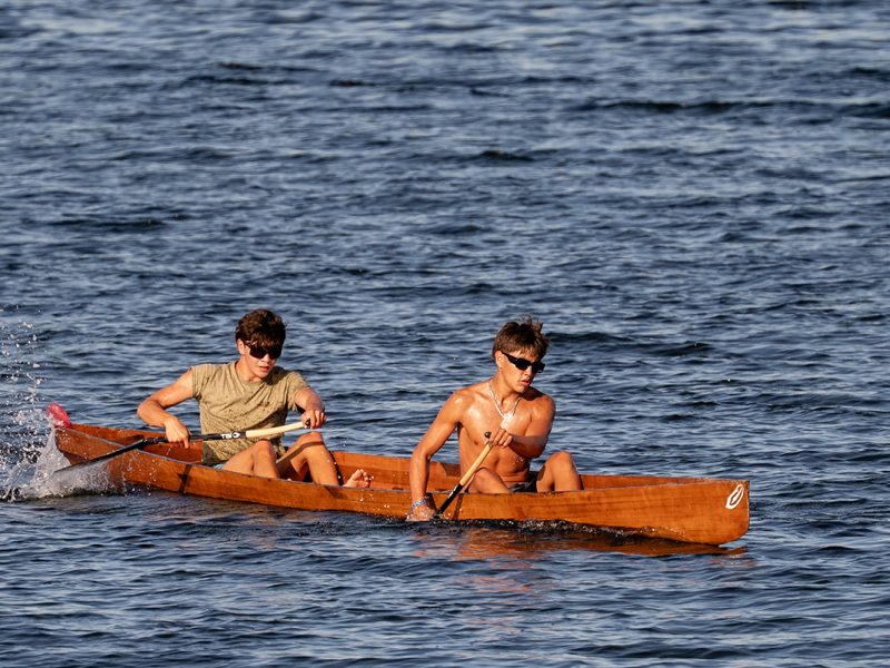 Two men paddle a wooden war canoe in a race