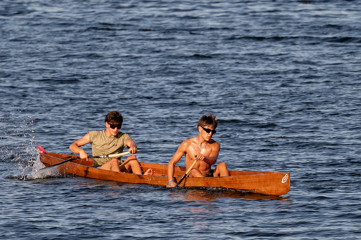 Two men paddle a wooden war canoe in a race