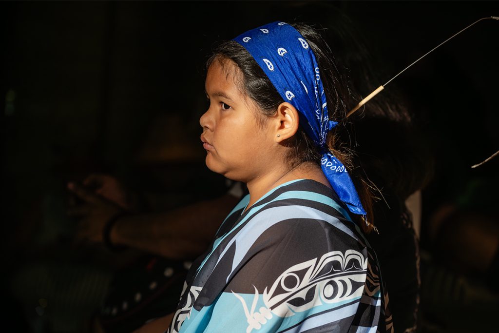 A girl watches drumming and dancing in the longhouse at Snuneymuxw Days 2025.
