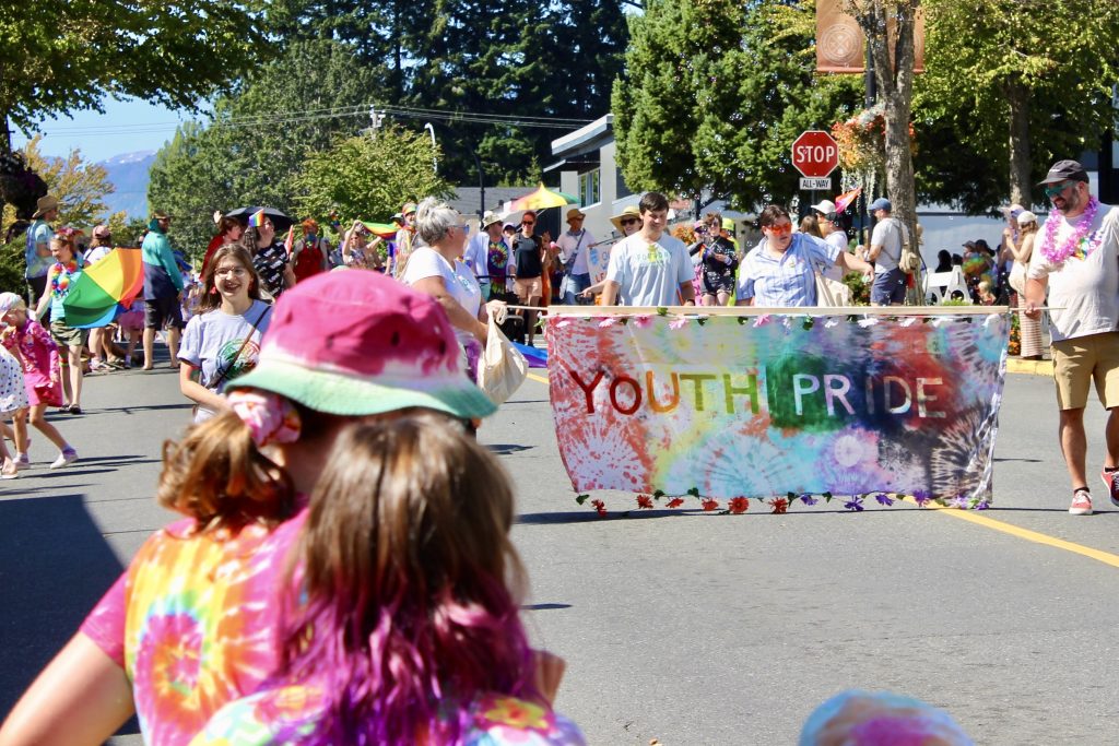 During a parade, a large banner is held up that says 'Youth Pride'
