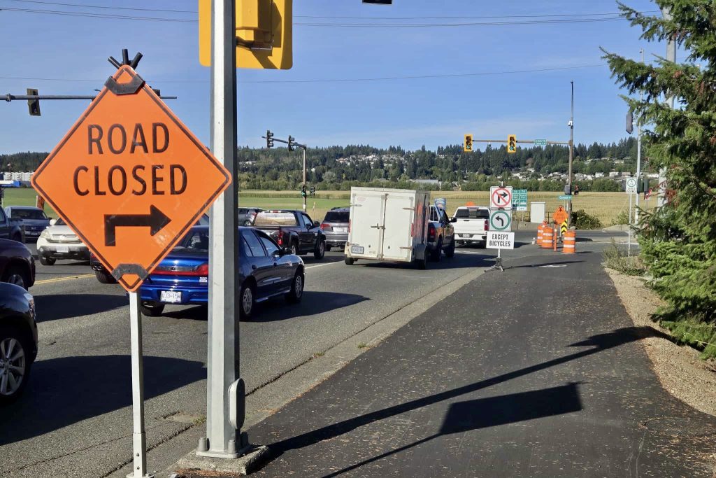 Road closed sign with an arrow pointing to the right. To the left is traffic.