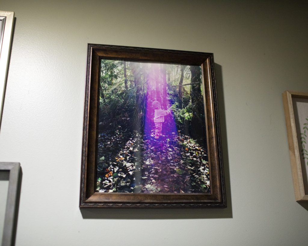 A framed photo of Kai as a toddler hanging on the wall. Kai appears to be in a forested area in the photo.