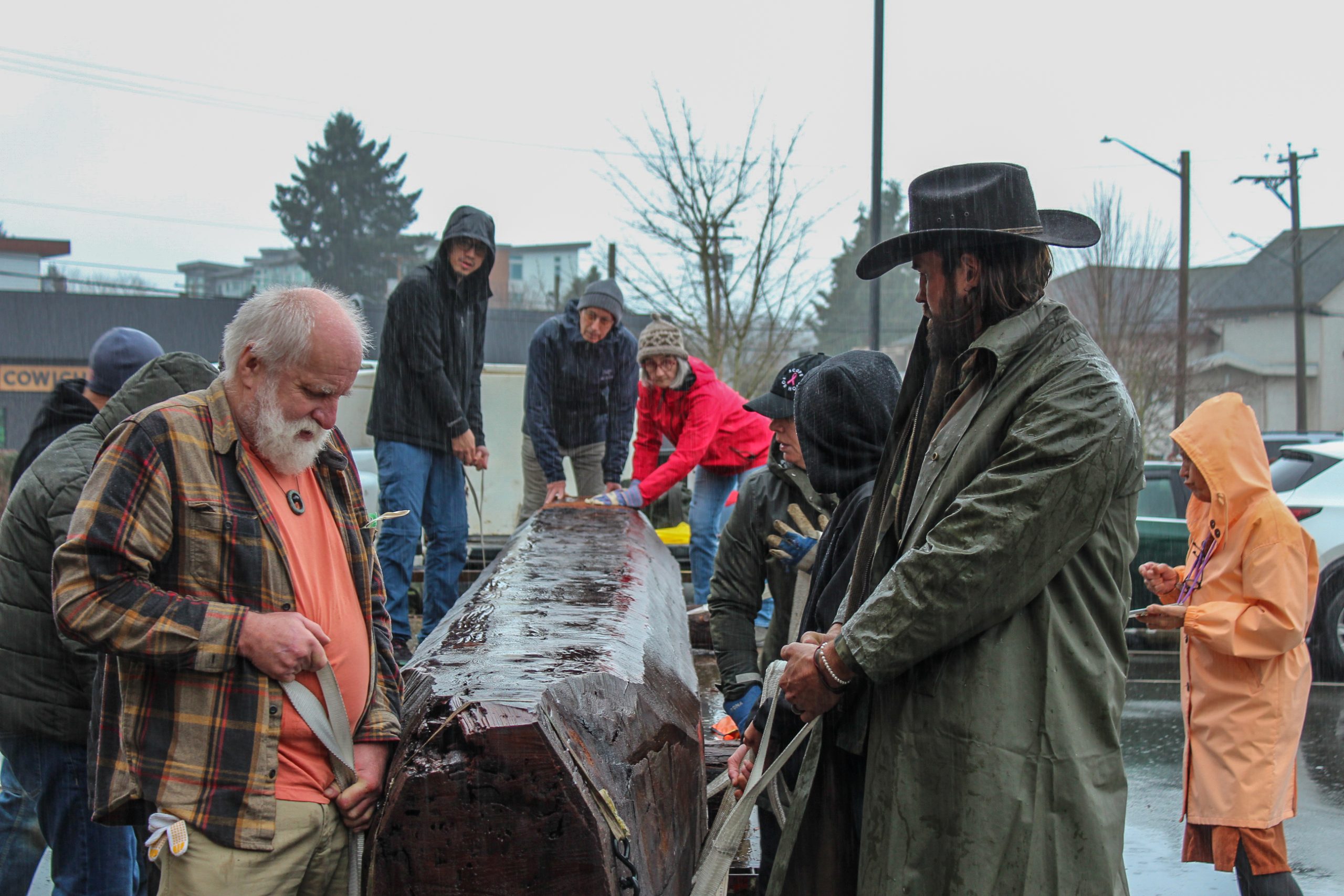 Voulenteers stand on either side of cedar log that is being transported into the Cowichan Valley Arts Council Gallery.