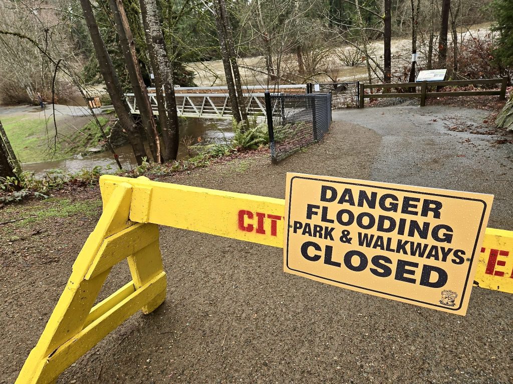 A danger sign and barricade blocks access to Puntledge Park. The sign reads Danger flooding closed