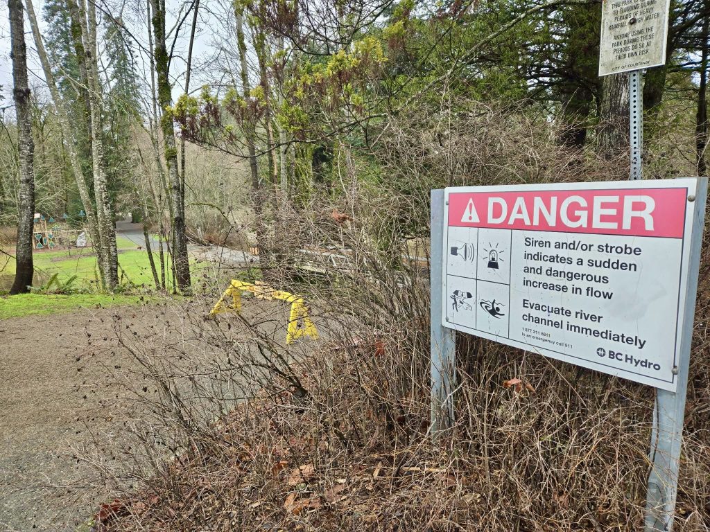 A sign along the Puntledge river describes the warning system — of sirens and strobe lights — in case of dangerous water flows and flood.