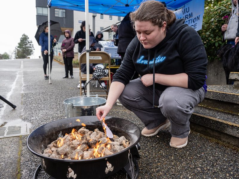 Hilary Nester, a social service worker student, burns a heart with a name of someone they were close to who died from the toxic drug crisis at a Grief Fire event at Vancouver Island University on April 14, 2026. Photo by Mick Sweetman / The Discourse.