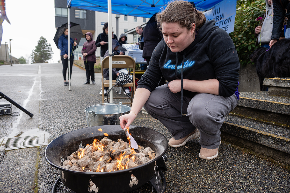 Hilary Nester, a social service worker student, burns a heart with a name of someone they were close to who died from the toxic drug crisis at a Grief Fire event at Vancouver Island University on April 14, 2026. Photo by Mick Sweetman / The Discourse.