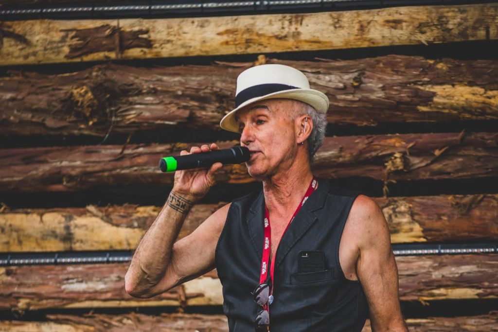 Avigdor Schulman, known to have supported the music scene in Cumberland, speaks holding a microphone while wearing a black leather vest and white and black fedora.
