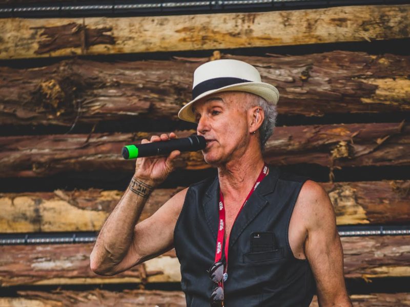 Avigdor Schulman, known to have supported the music scene in Cumberland, speaks holding a microphone while wearing a black leather vest and white and black fedora.