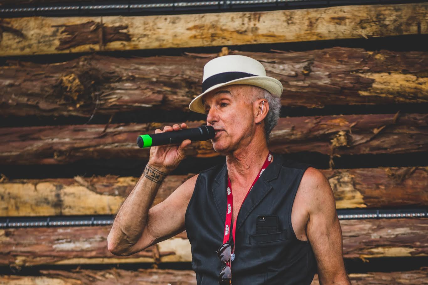 Avigdor Schulman, known to have supported the music scene in Cumberland, speaks holding a microphone while wearing a black leather vest and white and black fedora.