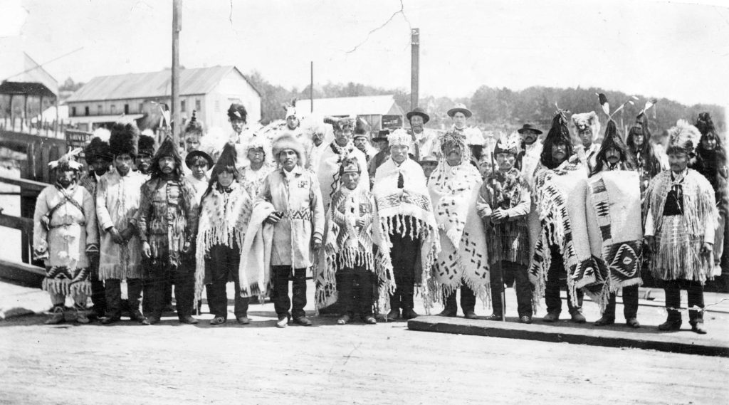 Chief Joe Capilano (centre, with a blanket draped over his arm) poses with other First Nations members on the North Vancouver Ferry Wharf before he leaves for England to petition King Edward VII in 1906. Photo courtesy of the Vancouver Archives.