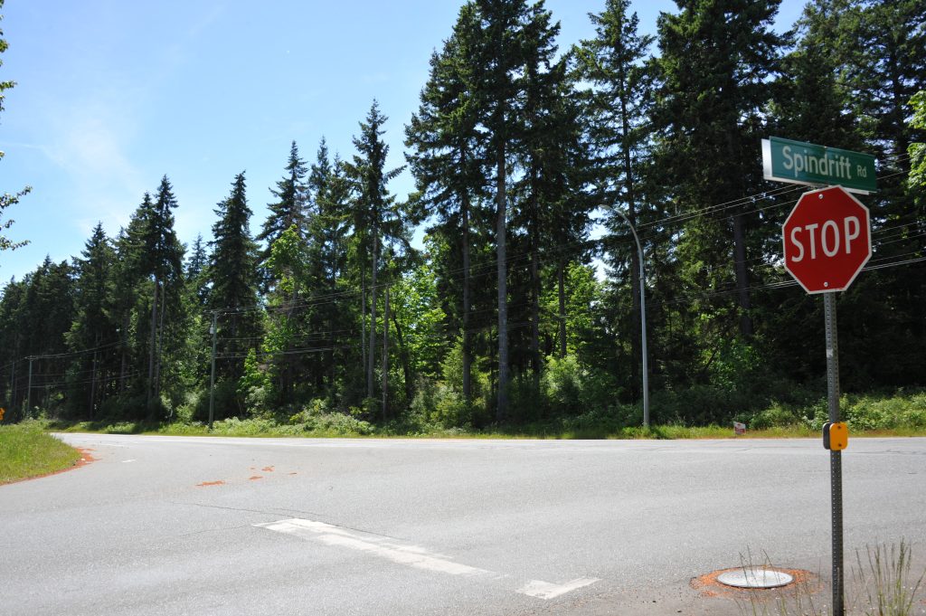 An image of a crossroad, with a stop sign on the far right, taken from K'ómoks First Nation territory that is included in the treaty.
