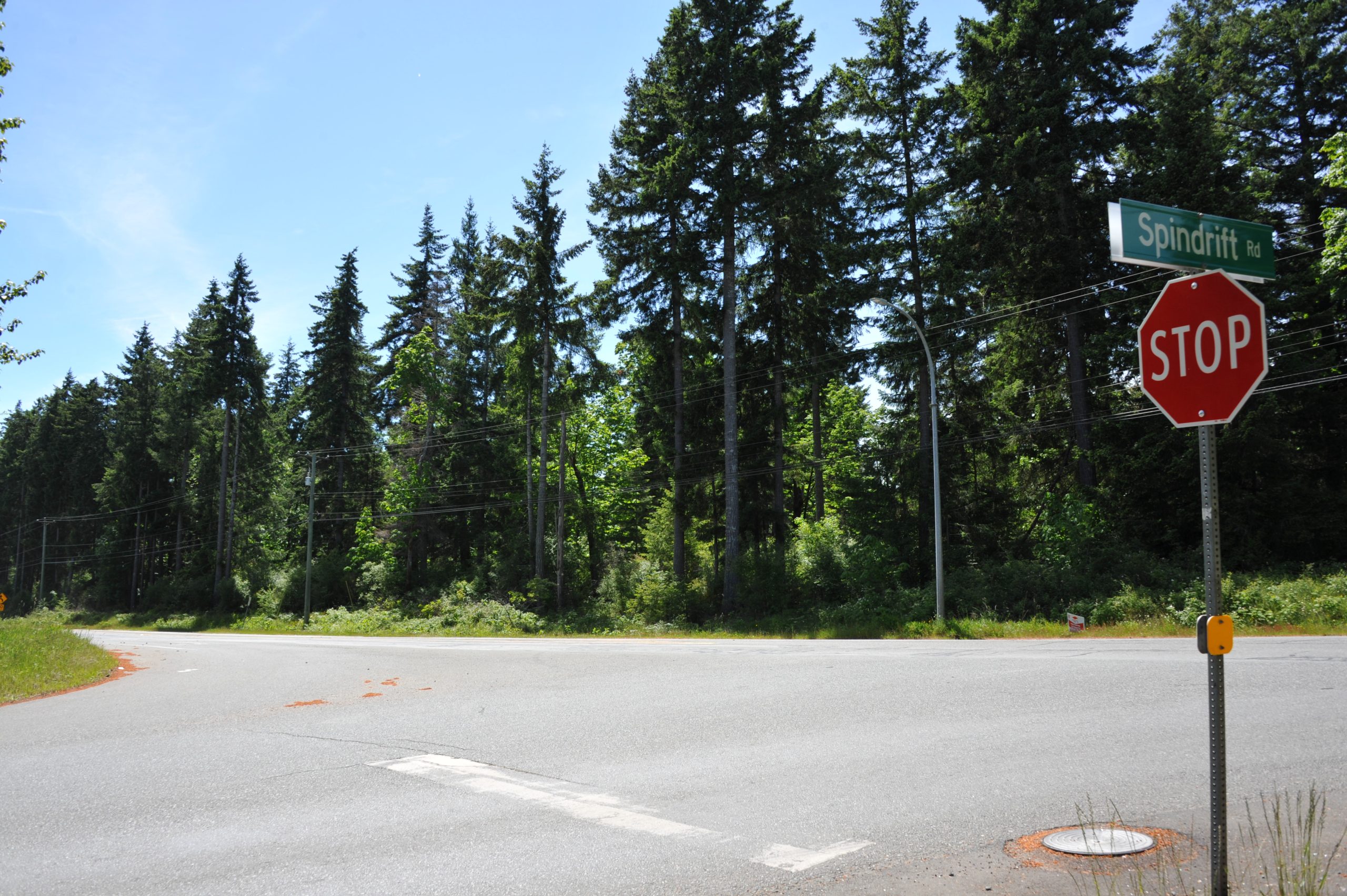 An image of a crossroad, with a stop sign on the far right, taken from K'ómoks First Nation territory that is included in the treaty.