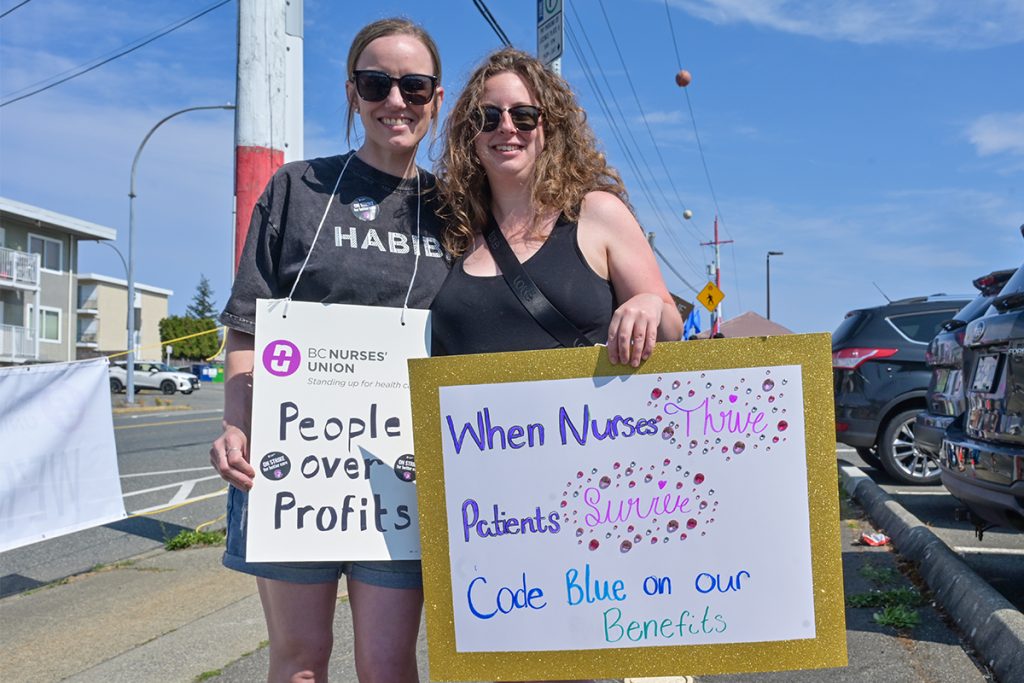 Emergency department nurses Marnie Boers (left) and Georgia Norton-Hall stand on a picket line outside the Nanaimo Regional General Hospital during a strike on July 13, 2026.