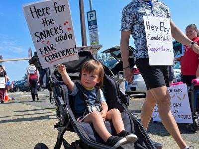 A young child holds a picket sign during the nurses strike at the Nanaimo Regional General Hospital on July 13, 2026.