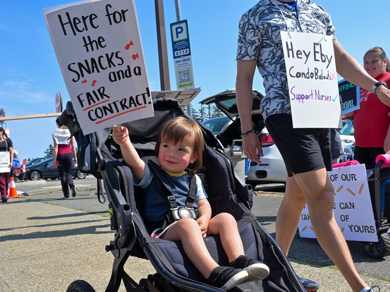A young child holds a picket sign during the nurses strike at the Nanaimo Regional General Hospital on July 13, 2026.