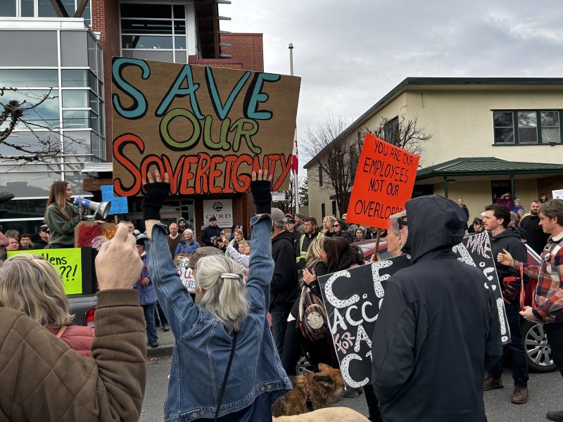 A crowd of people protesting in front of the CVRD building with posters and signs in hand. One sign says Save Our Sovereignty