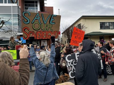 A crowd of people protesting in front of the CVRD building with posters and signs in hand. One sign says Save Our Sovereignty
