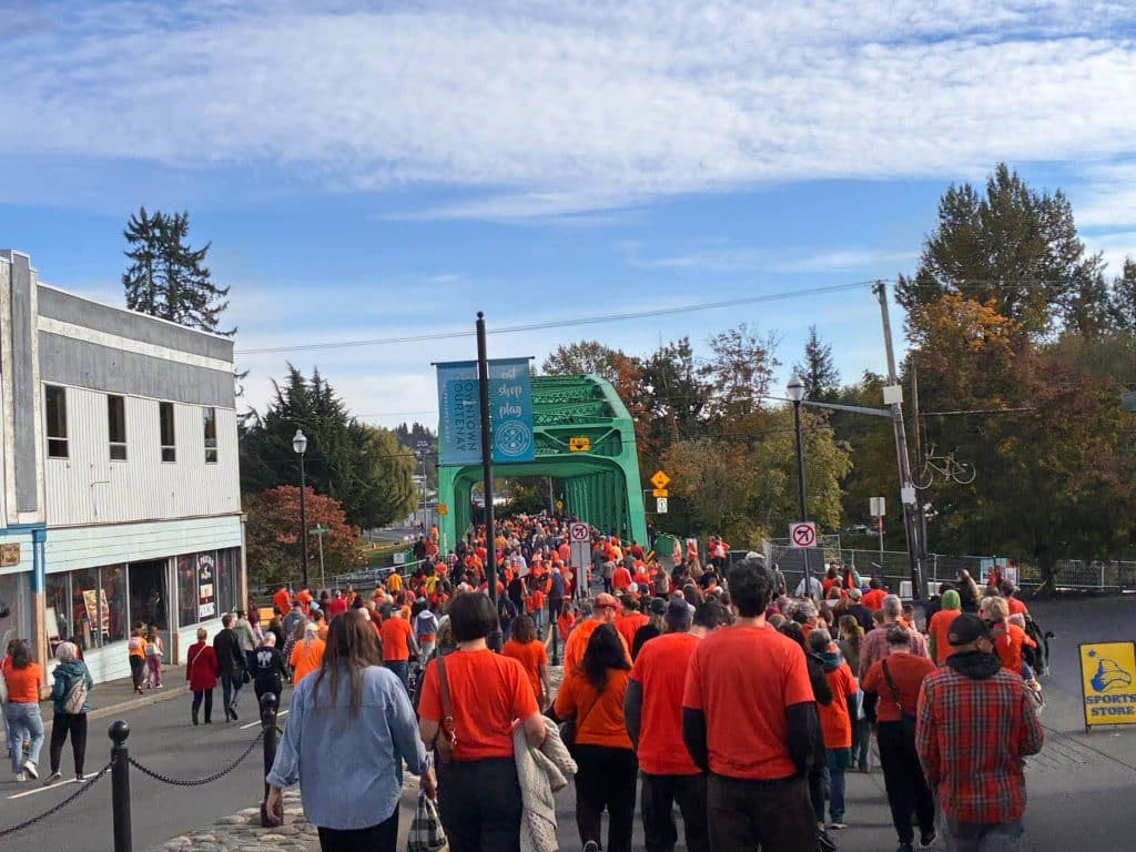 People dressed in orange for TRC day walk down the street.